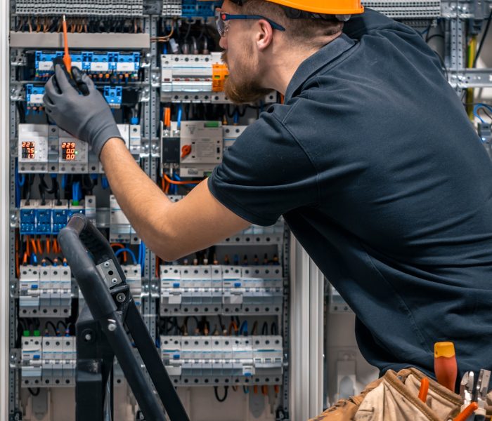 Male electrician working in a switchboard with fuses.
